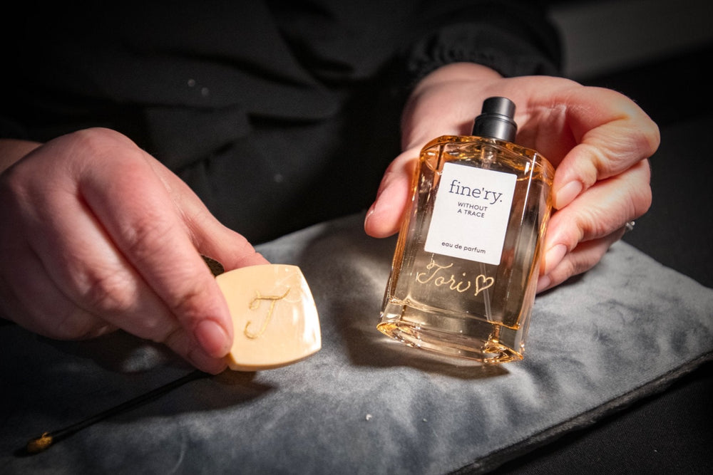 NYC calligrapher and engraver The Poppy Pen showcasing a Fine'ry perfume bottle personalized with elegant gold script for a live brand event.