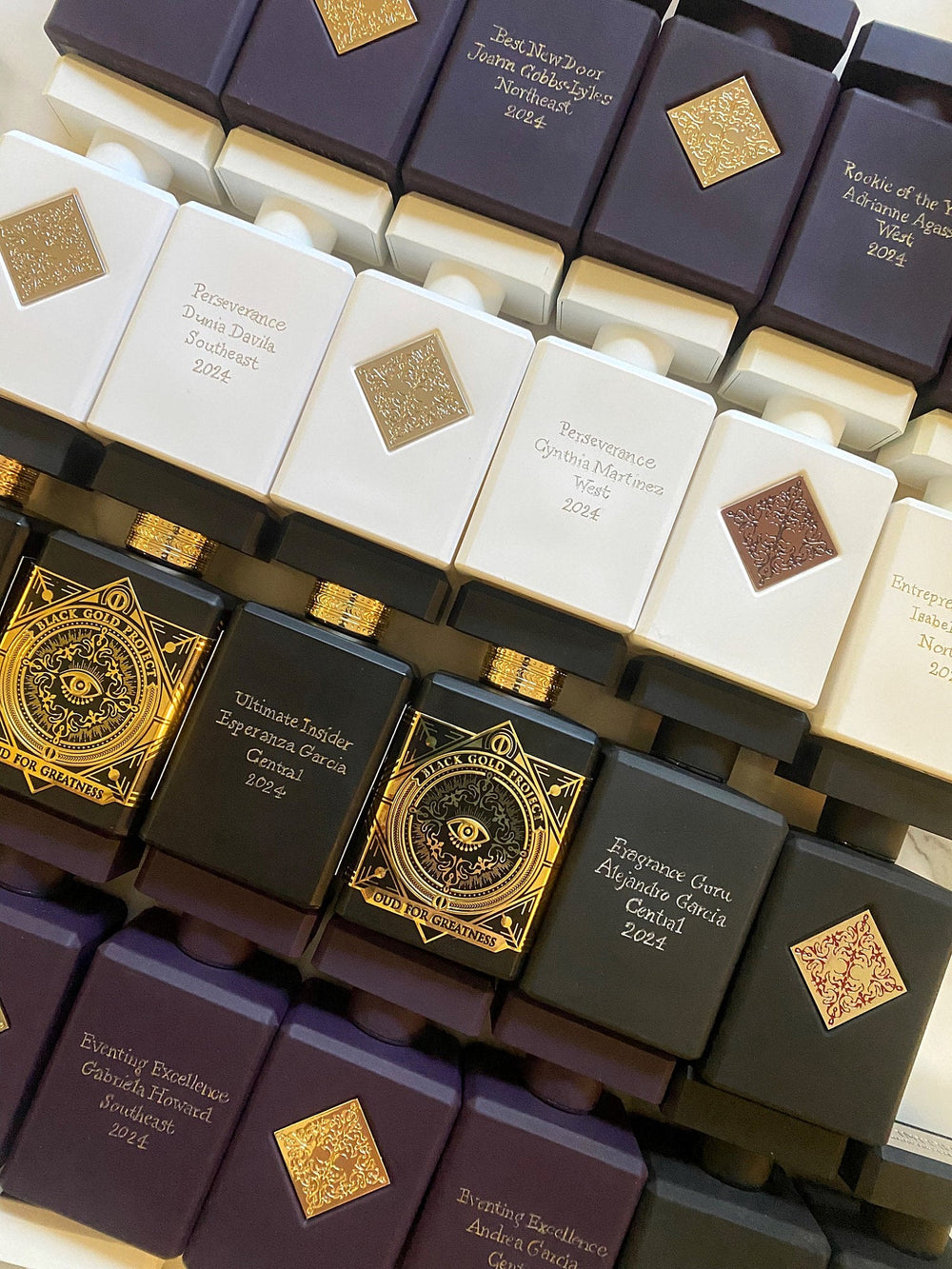 Collection of custom engraved Initio Parfums Privés fragrance bottles personalized with recipients’ names and award titles for a luxury corporate awards event.