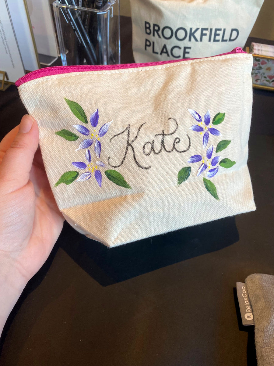 Personalized canvas pouch with hand-lettered calligraphy and purple floral painting at Brookfield Place in New York City.