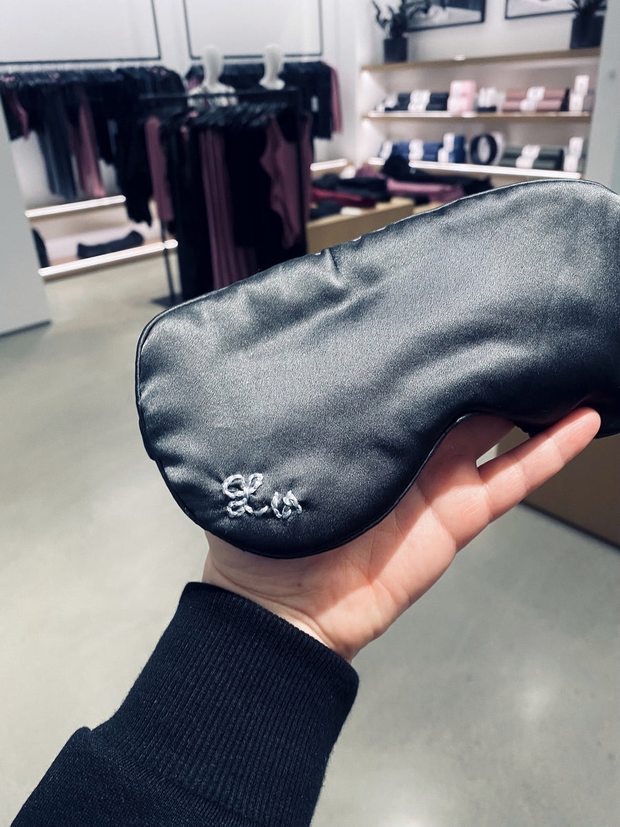 Close-up of personalized embroidery on a black silk Brooklinen sleep mask at an Alo brand activation.