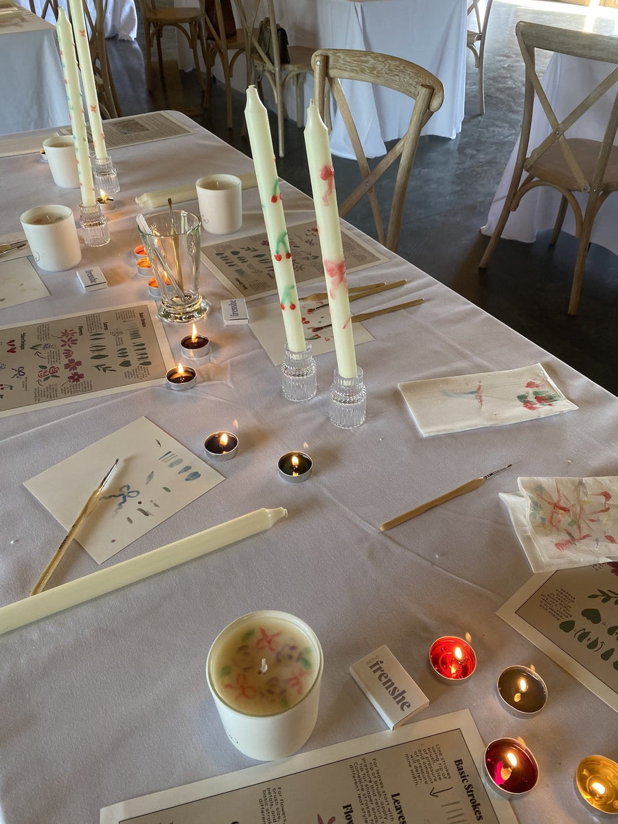 Hand-painted taper candles and personalized Being Frenshe candles displayed during a creative wellness retreat.