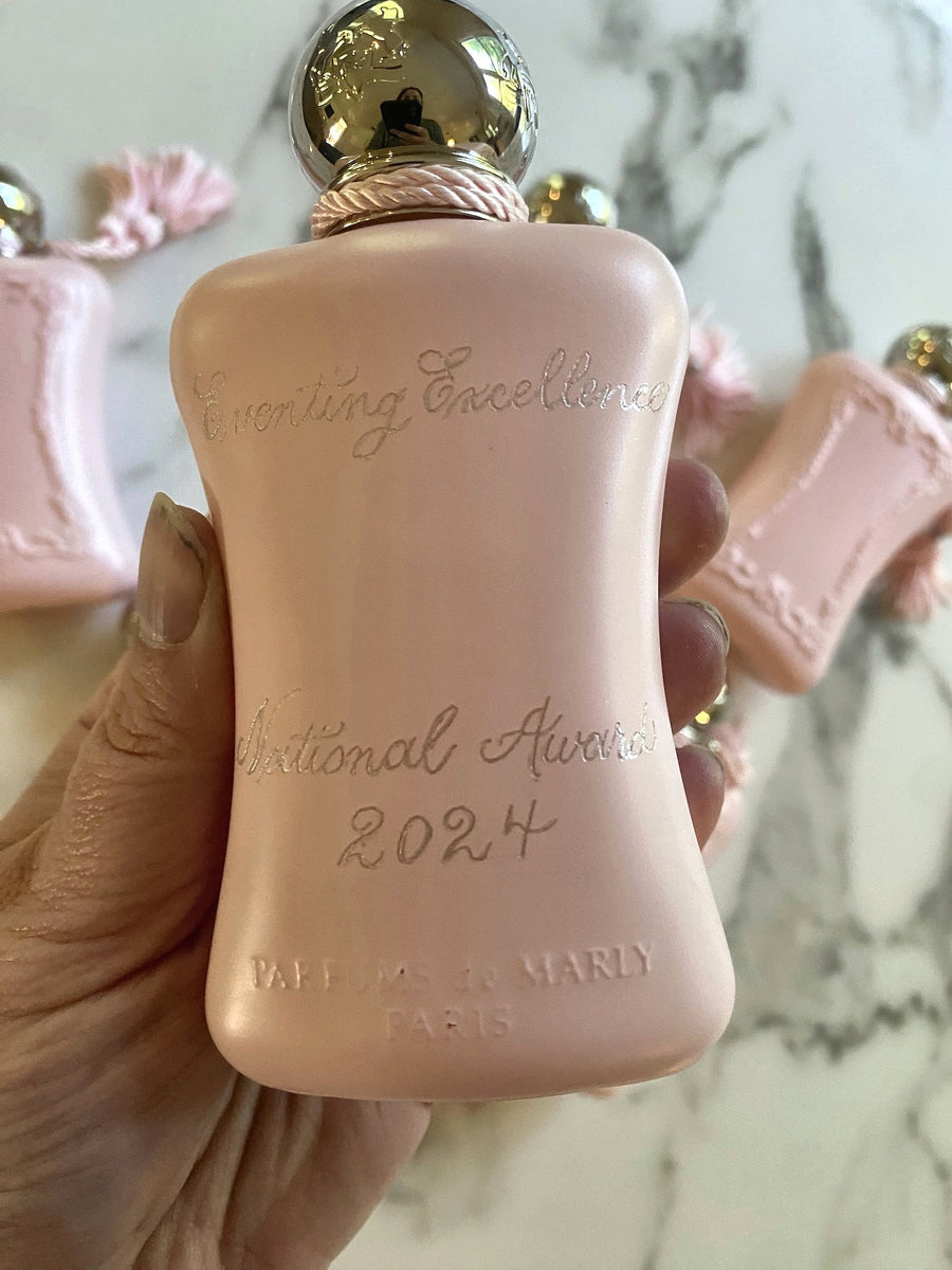Close-up of a pink Parfums de Marly Delina bottle with custom silver-filled calligraphy engraving for the 2024 Eventing Excellence award.