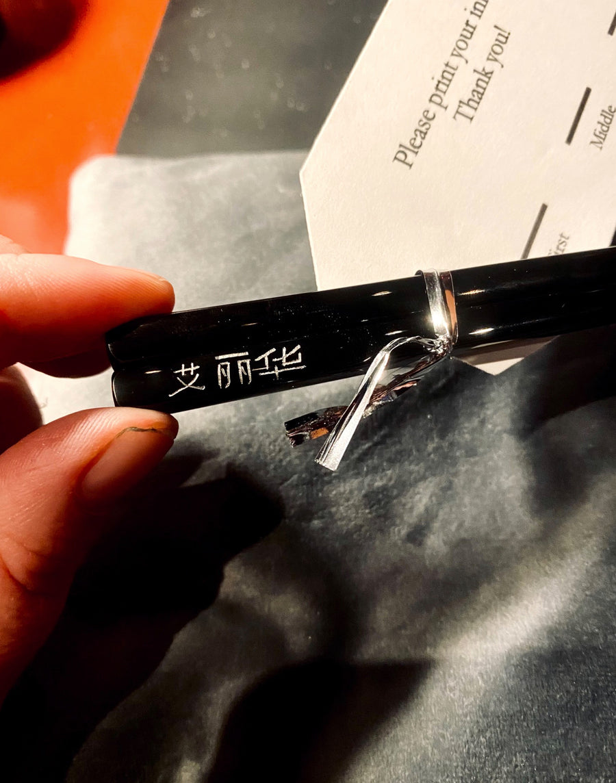 Personalized black chopsticks featuring hand-engraved Chinese characters and a silver ribbon at a New York City corporate event.