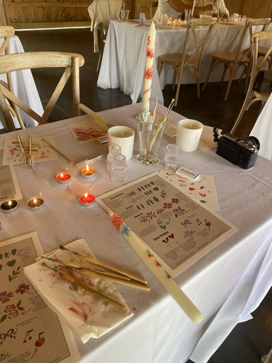 Candle painting workshop setup with custom artwork, brushes, and decorated candles for a Being Frenshe brand activation.