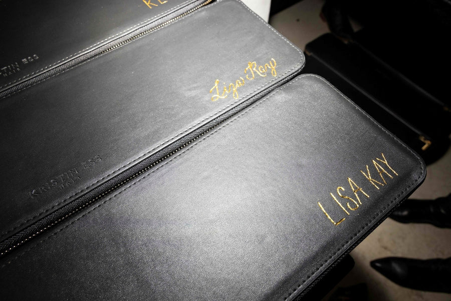 Custom gold-foiled names on black Kristin Ess leather accessories displayed during a luxury NYC brand activation.