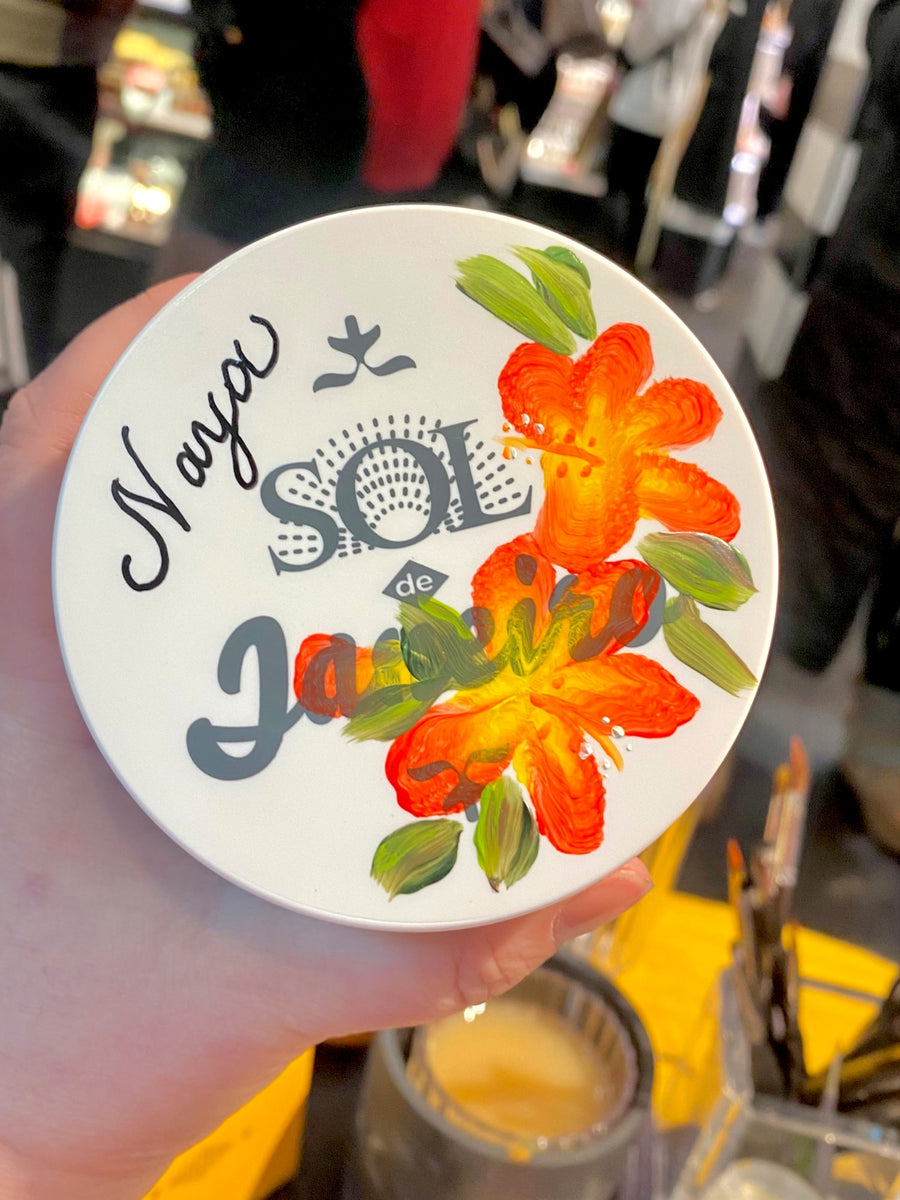 Sol de Janeiro Brazilian Bum Bum Cream lid customized with orange hibiscus flowers and a guest name in black calligraphy by The Poppy Pen.