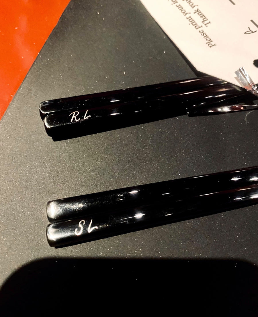 Two sets of black chopsticks personalized with hand-engraved initials for View the Space's corporate event in NYC.