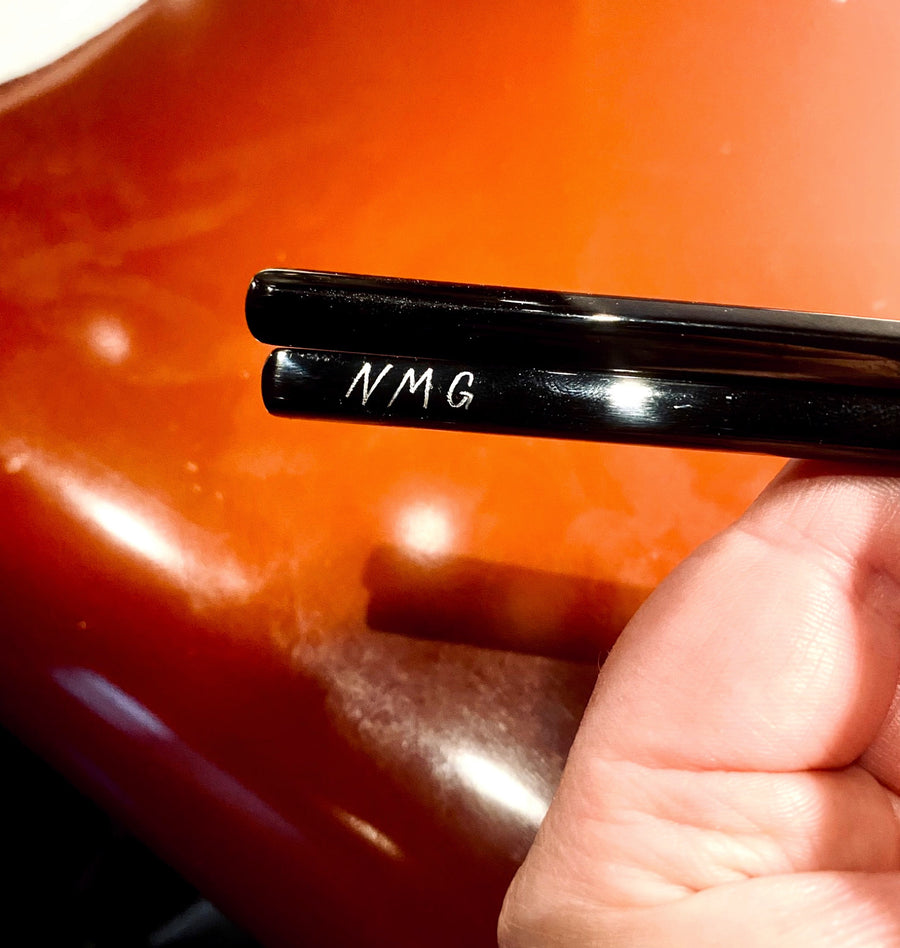 Close-up of white hand-engraved monogram lettering on glossy black chopsticks for a corporate event at Katsuya NYC.