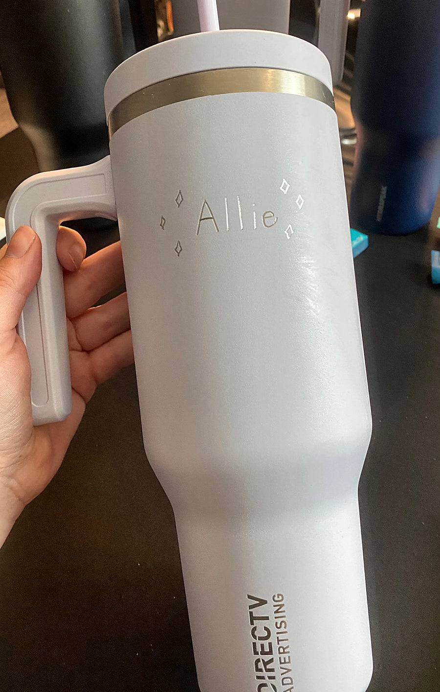Custom name engraving with decorative diamond details on a light blue tumbler at a DIRECTV Advertising event in New York City.