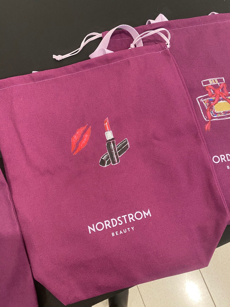 Custom lipstick and red lips illustration hand-painted on a purple Nordstrom Beauty tote bag during a live event painting activation in NYC.
