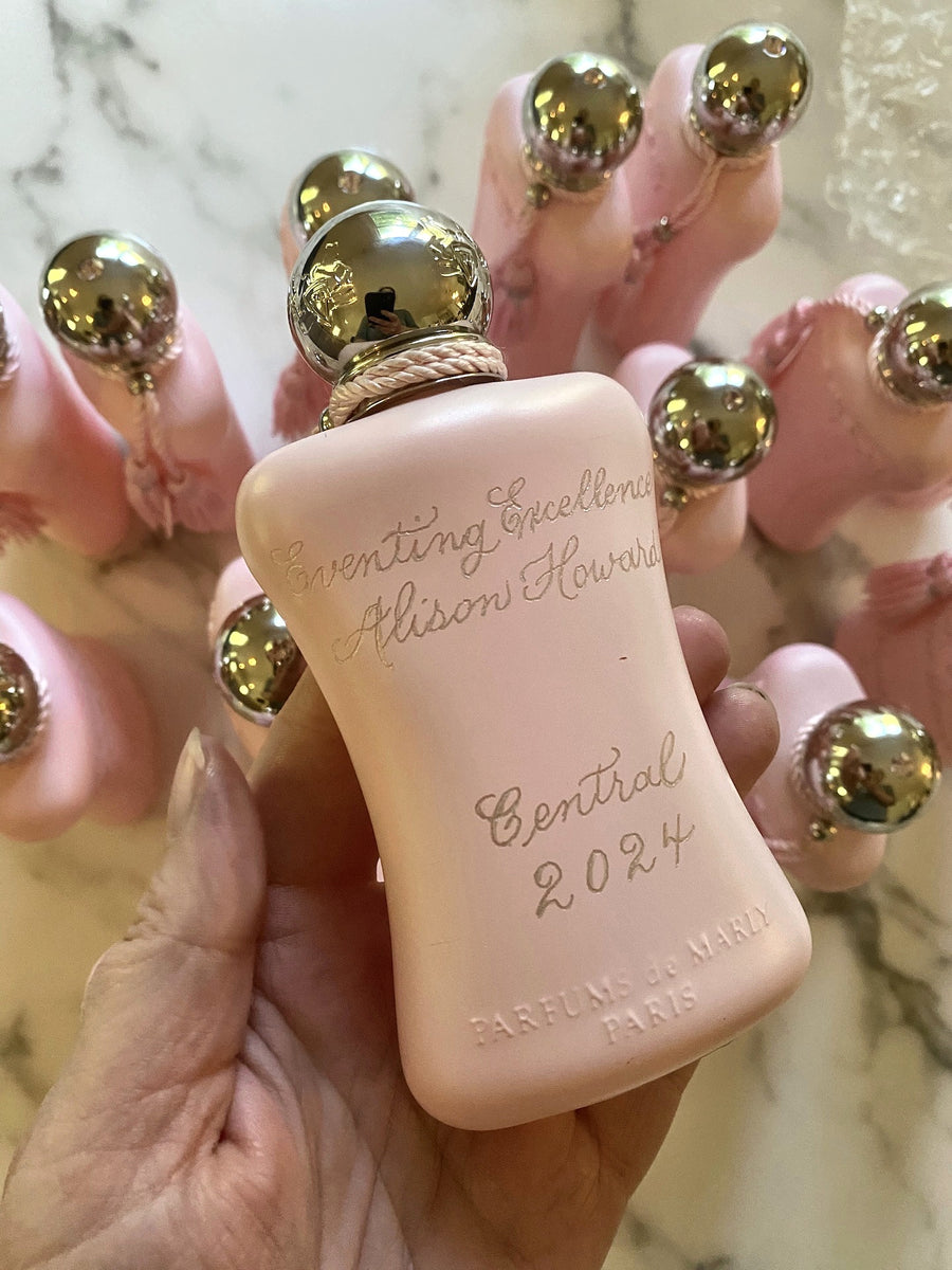 Collection of personalized Parfums de Marly Delina perfume bottles featuring custom engraved names and awards for luxury corporate gifting.