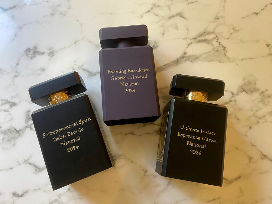 Three oversized Initio Parfums Privés fragrance bottles custom engraved with award titles and recipients' names.