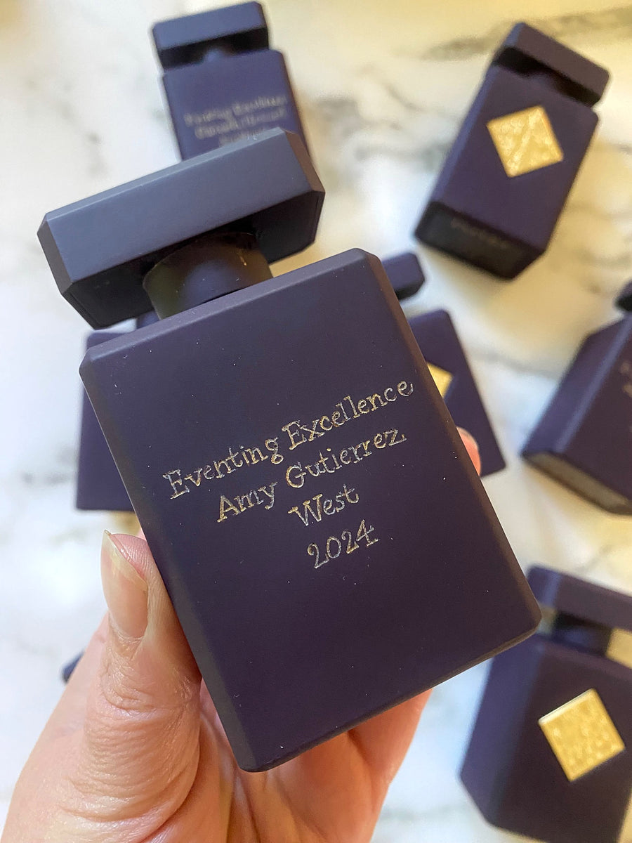 Close-up of a purple Initio Parfums Privés perfume bottle with personalized gold lettering for a corporate recognition award.